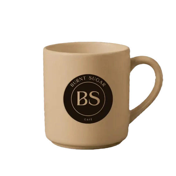 A caramel mug with Burnt Sugar's round logo.